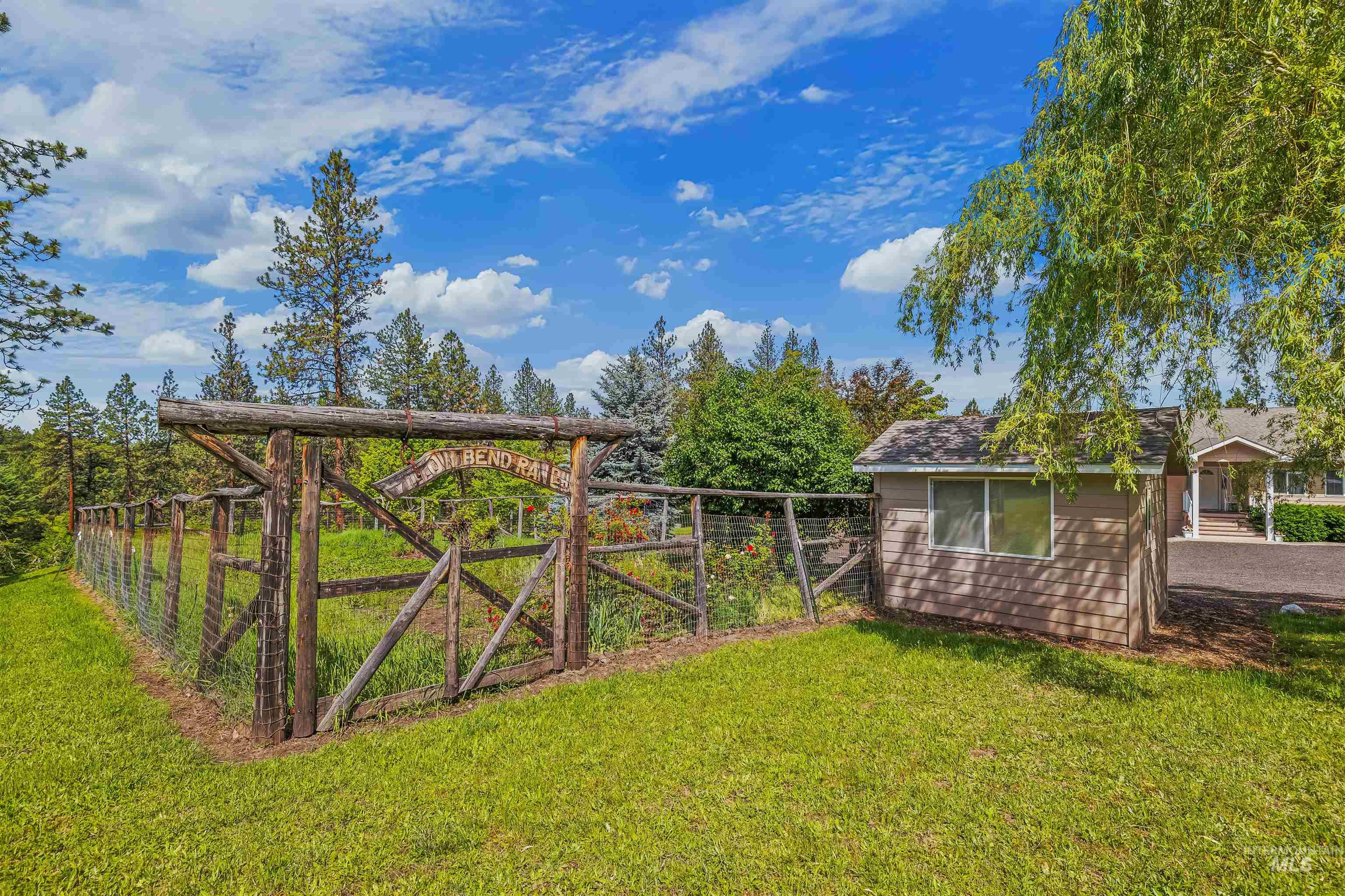 743 Wall Crk Road Stites, ID 83552 - Photo 6 of 48 Fenced garden area with a rustic timber gate, accompanied by a detached shed with horizontal siding and a shingled roof