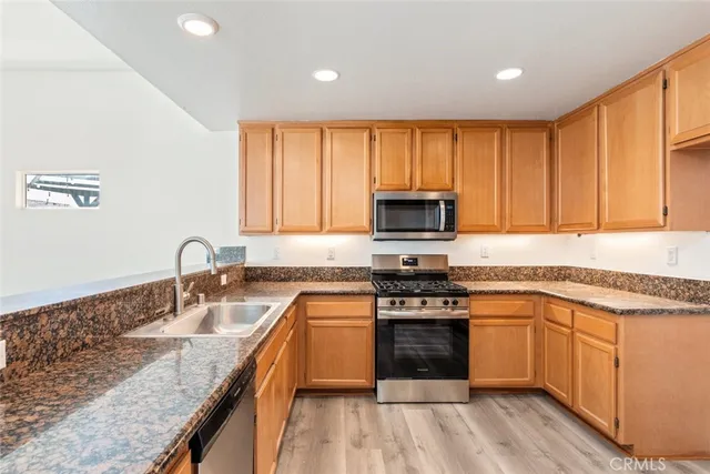 a kitchen with stainless steel appliances granite countertop a stove a sink dishwasher and a microwave oven with wooden floor