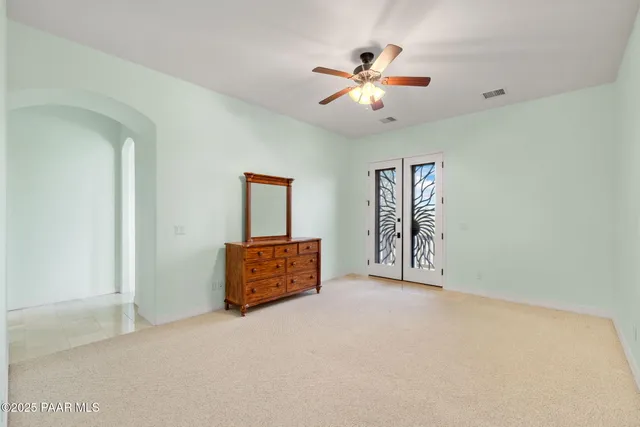 a view of an empty room with chandelier fan