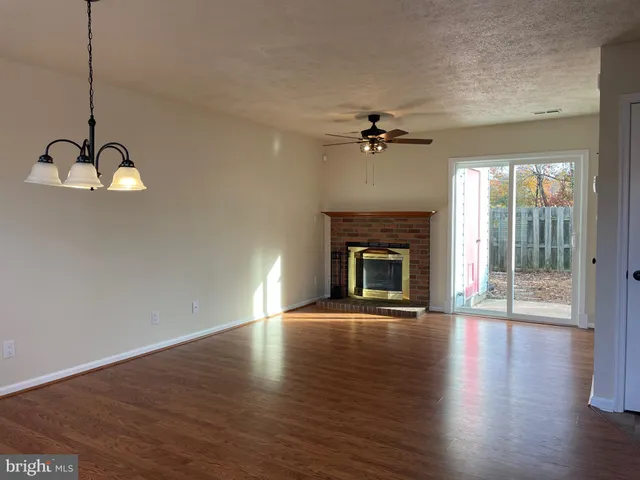 a view of an empty room with glass door and wooden floor