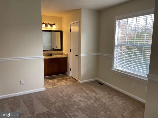 an empty room with a window and a kitchen view