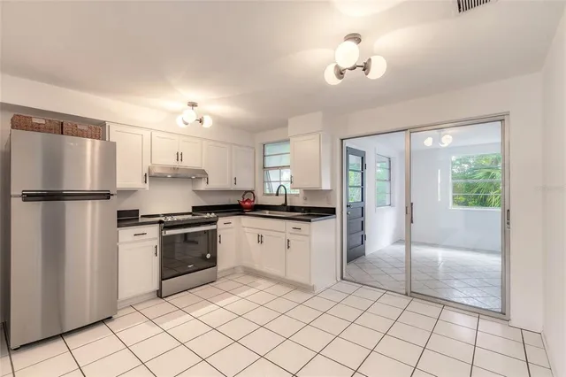 a kitchen with granite countertop a refrigerator and a stove top oven