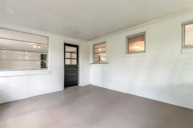 a view of an empty room with a window and a kitchen