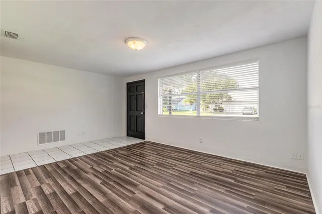 a view of an empty room with wooden floor and a window