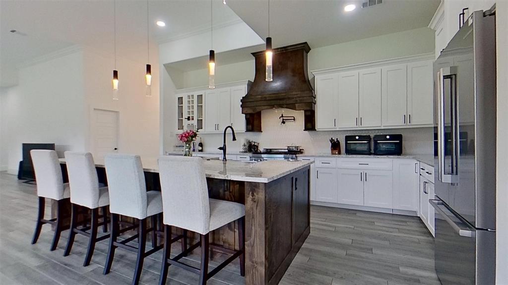 3248 North Cardinal Road Azle, TX 76020 - Photo 13 of 29 Spacious kitchen featuring a large island with seating, white cabinetry, integrated stainless steel appliances, a dark wood range hood, and tile flooring