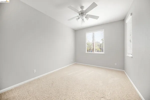 an empty room with windows and fan