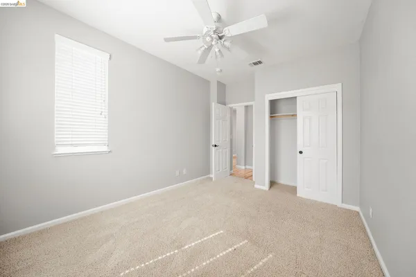 an empty room with windows and fan