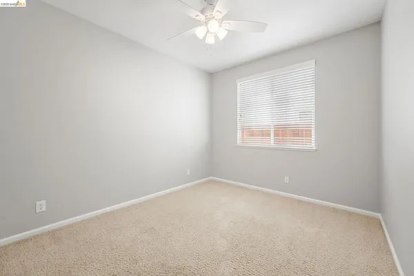 an empty room with a window and a fan