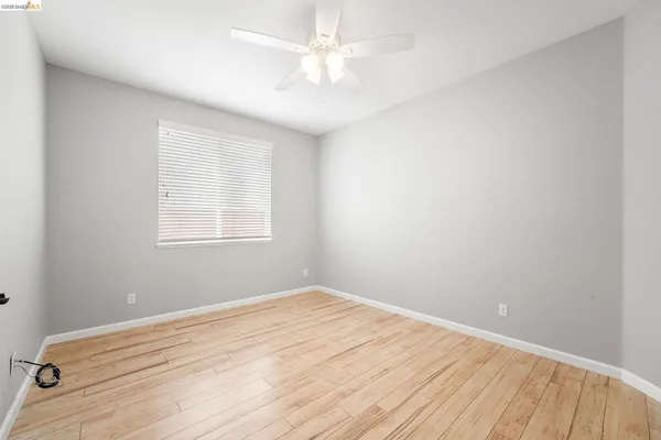 an empty room with a window and a ceiling fan