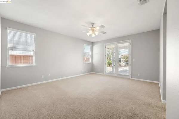 an empty room with windows and ceiling fan