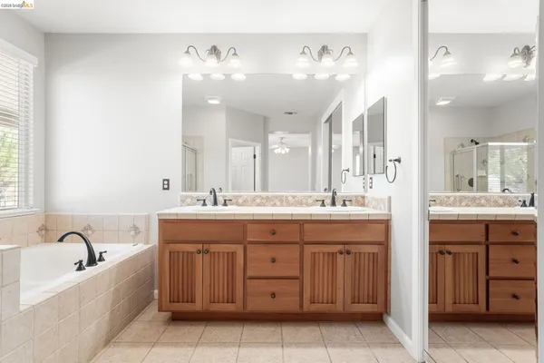 a spacious bathroom with a granite countertop sink a mirror a vanity and bathtub