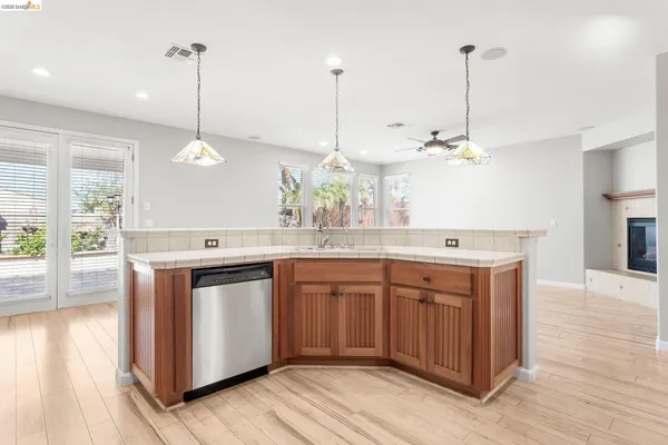 a kitchen with stainless steel appliances granite countertop wooden cabinets and a wooden floor