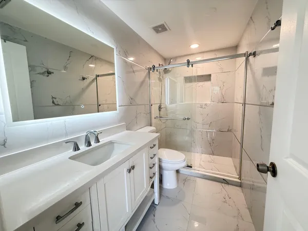 a bathroom with a double vanity sink toilet and shower