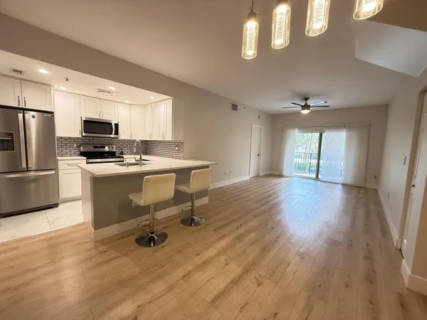 a kitchen with a sink a refrigerator and wooden floor