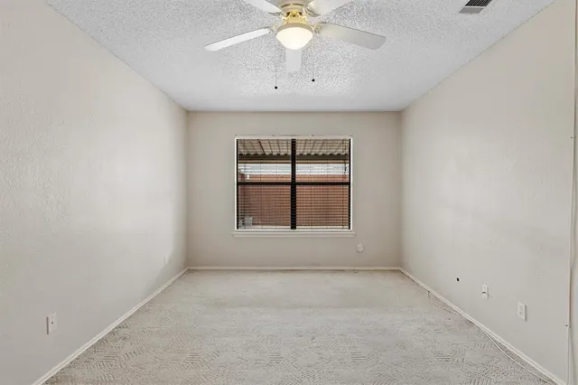 an empty room with a window and a fan