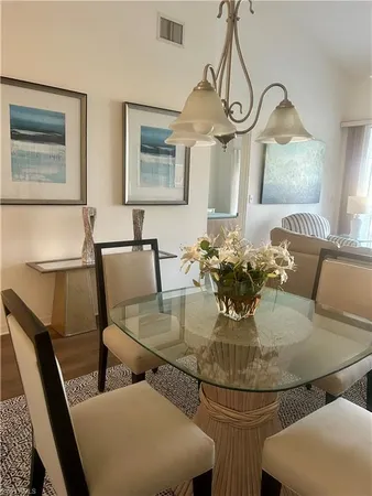 a dining room with wooden floor a chandelier a glass table and chairs