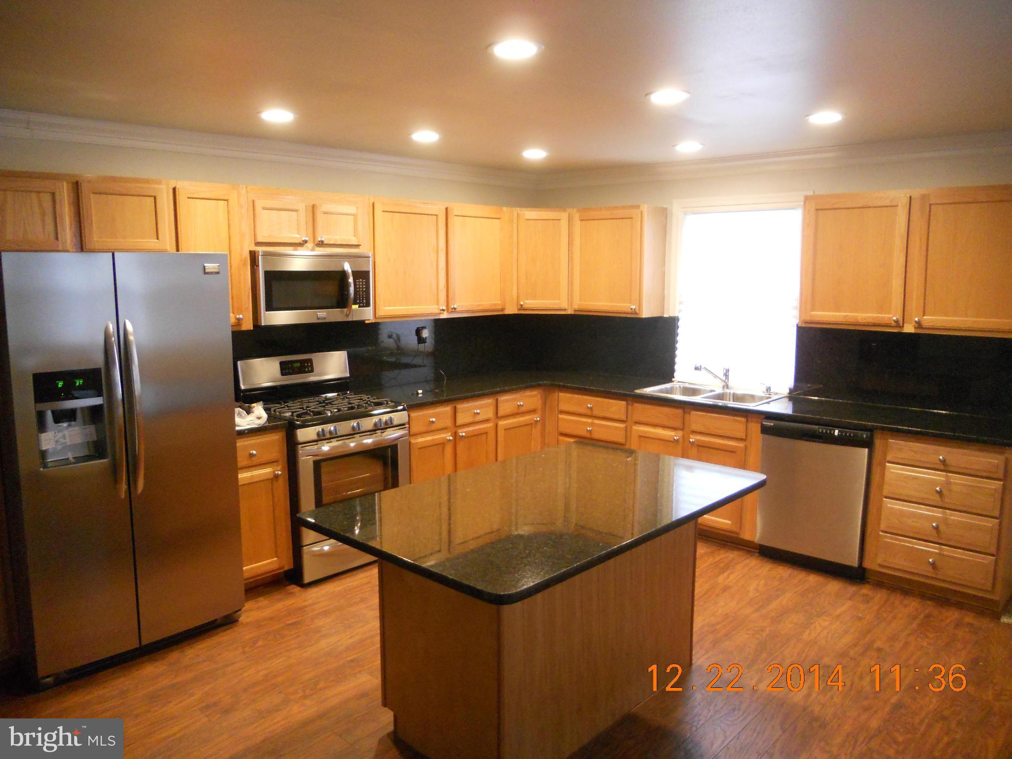 937 Coleridge Road Baltimore, MD 21229 - Photo 5 of 16 a kitchen with stainless steel appliances granite countertop a refrigerator a stove top oven a sink with island and chairs