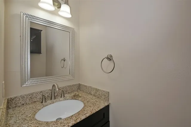 a bathroom with a granite countertop sink a mirror and a shower