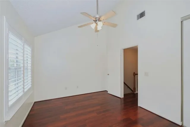 a view of an empty room with a window and wooden floor