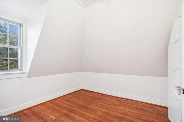 an empty room with wooden floor and fan