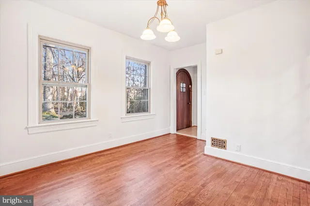 an empty room with wooden floor chandelier fan and windows