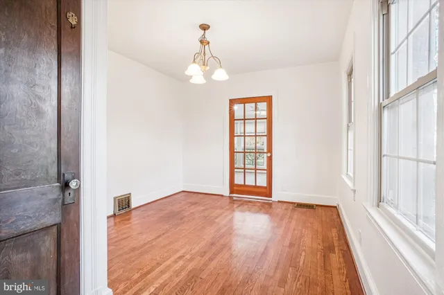 an empty room with wooden floor cabinet and windows