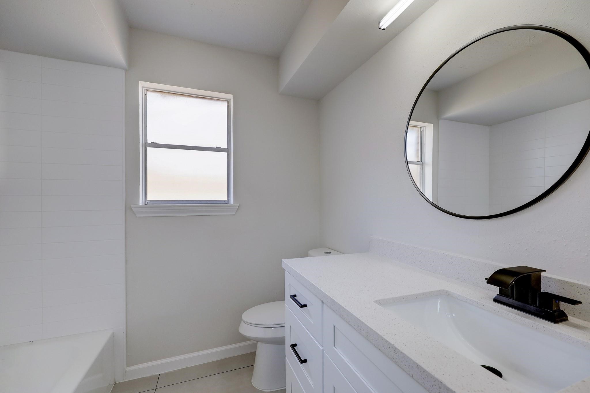 9723 Galston Lane Spring, TX 77379 - Photo 19 of 24 This bathroom includes a stylish vanity with matte black fixtures, a round mirror, and a window that brings in natural brightness—contemporary and functional.