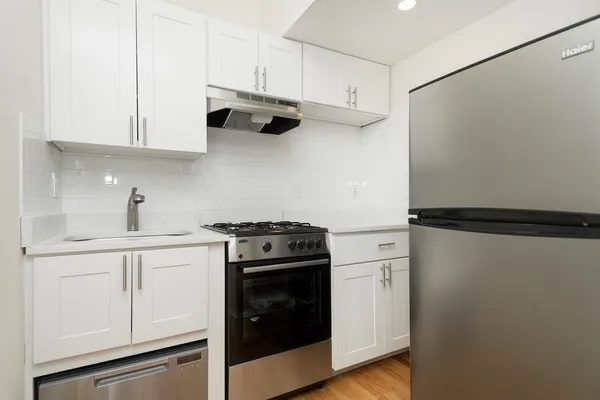 a kitchen with stainless steel appliances white cabinets and a refrigerator