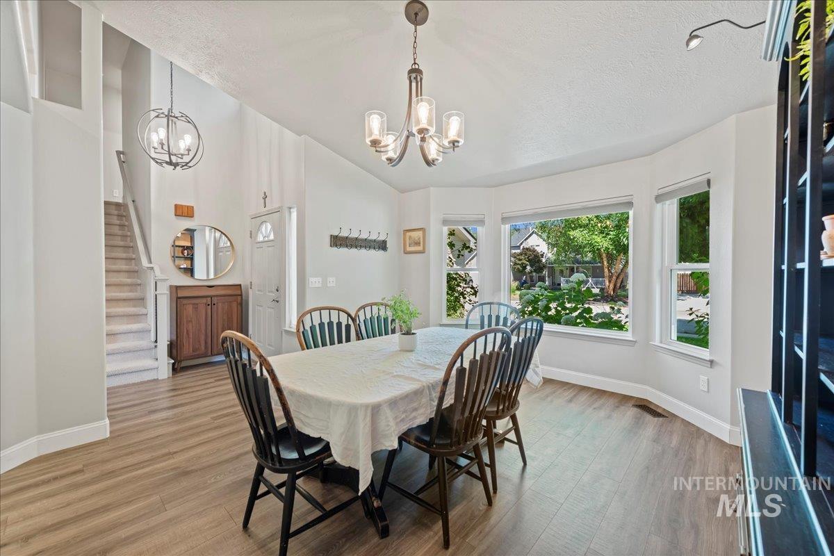 3411 North Summercrest Way Meridian, ID 83646 - Photo 11 of 30 Dining room with a chandelier, stairs, a textured ceiling, light wood-type flooring, and high vaulted ceiling