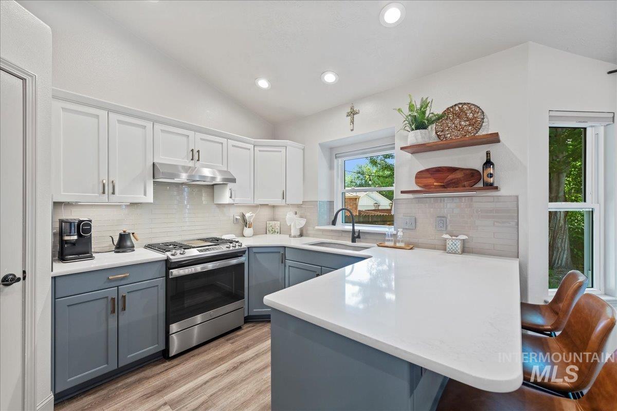 3411 North Summercrest Way Meridian, ID 83646 - Photo 13 of 30 Kitchen featuring stainless steel gas stove, open shelves, gray cabinetry, a peninsula, and under cabinet range hood