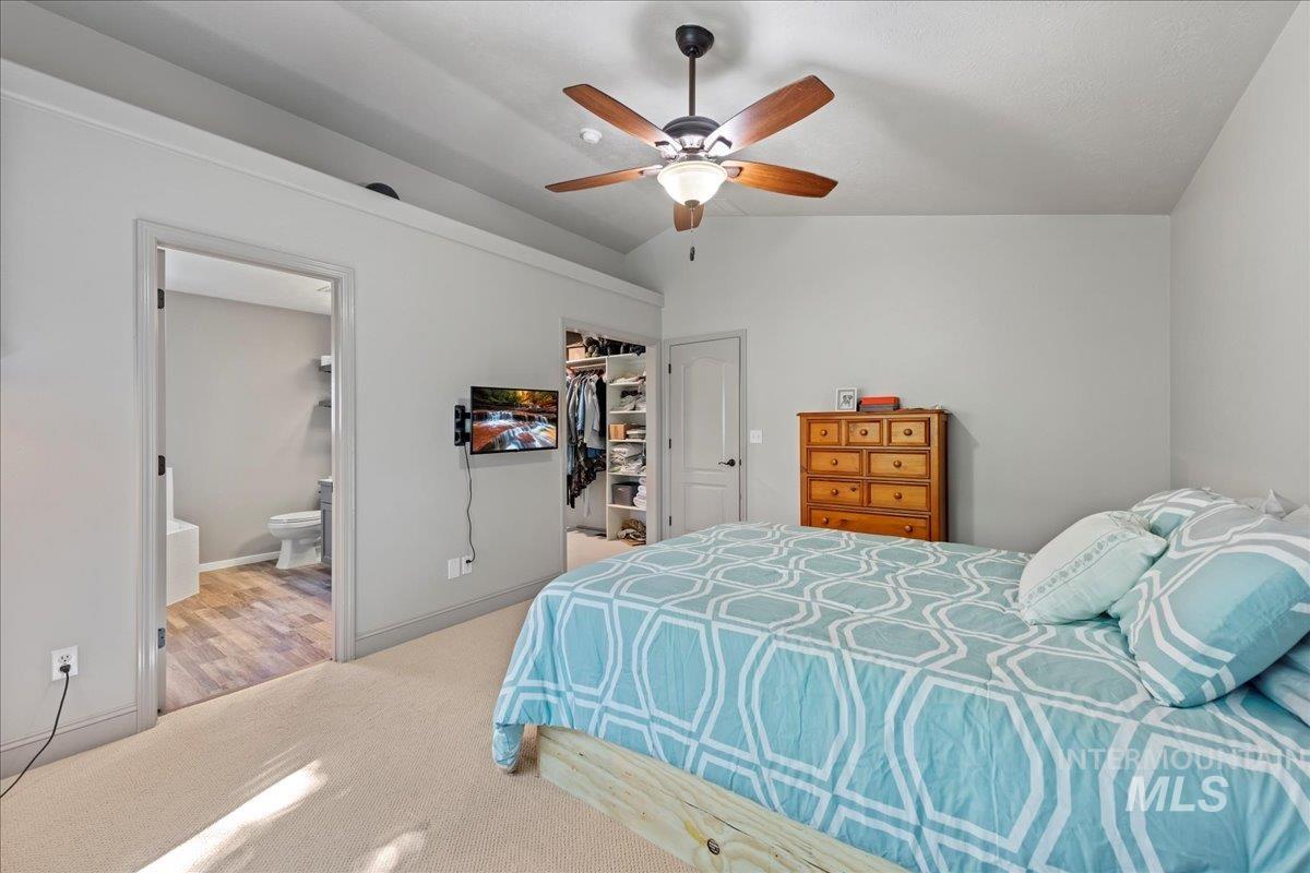 3411 North Summercrest Way Meridian, ID 83646 - Photo 15 of 30 Carpeted bedroom featuring vaulted ceiling, ensuite bath, a spacious closet, a ceiling fan, and a closet
