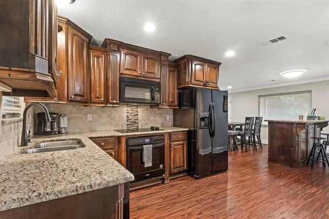 a kitchen with stainless steel appliances granite countertop a refrigerator stove top oven and sink