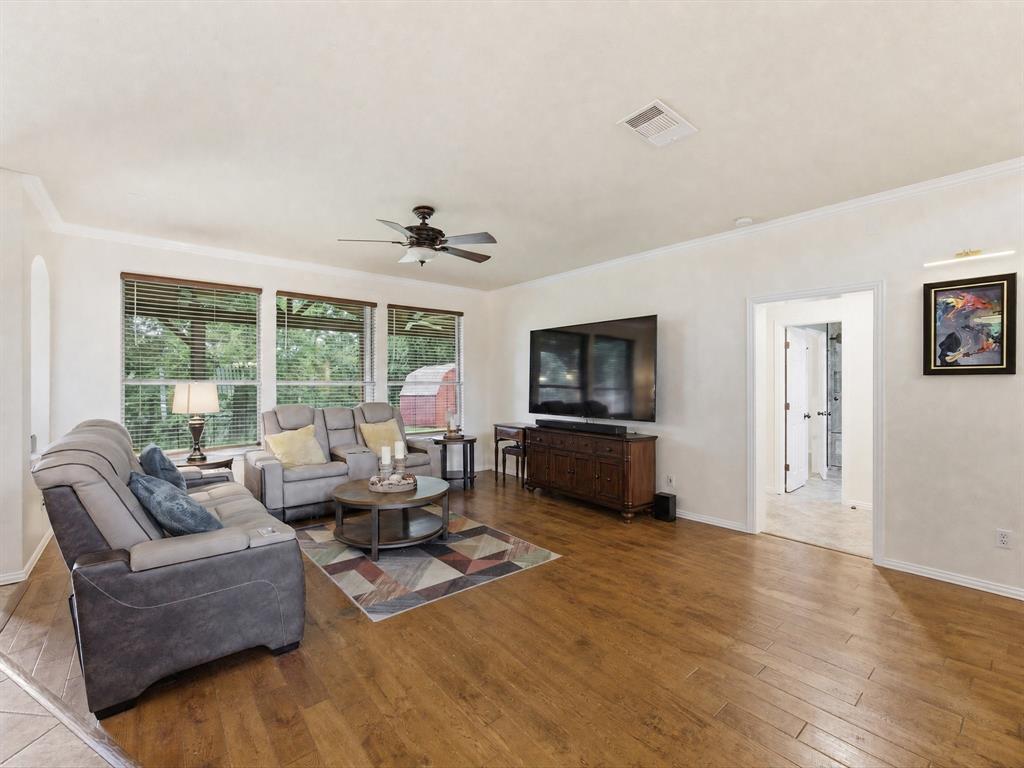 4008 Falcon Ridge Drive Haltom City, TX 76137 - Photo 16 of 40 Spacious living area featuring wood-finish flooring, white baseboards, and a ceiling fan with integrated lighting