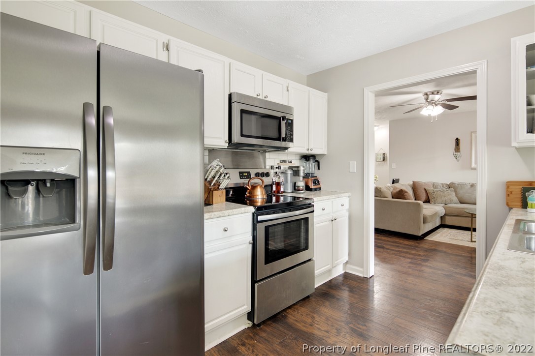 7096 Rockfish Road Raeford, NC 28376 - Photo 15 of 40 a kitchen with stainless steel appliances kitchen island granite countertop a refrigerator a stove a sink and a dining table with wooden floor