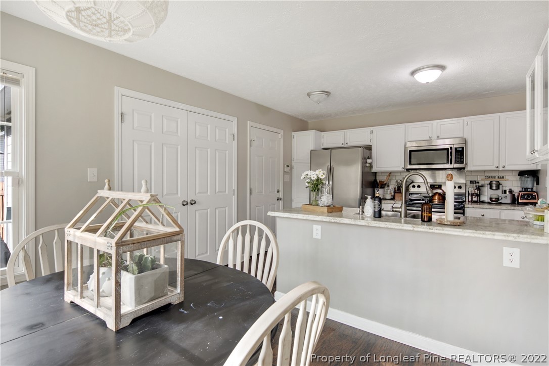 7096 Rockfish Road Raeford, NC 28376 - Photo 19 of 40 a kitchen with stainless steel appliances granite countertop a stove a sink a refrigerator white cabinets with wooden floor