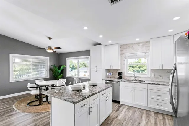 a kitchen with kitchen island granite countertop a sink stove and refrigerator