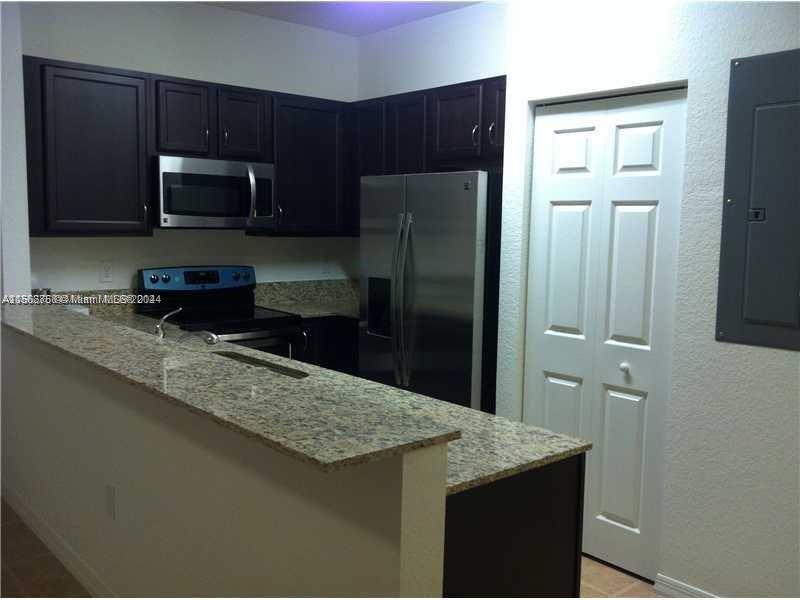 a kitchen with stainless steel appliances granite countertop a refrigerator a stove a sink and dishwasher
