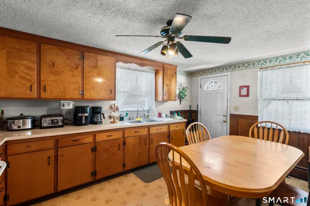 a kitchen with stainless steel appliances granite countertop a sink a refrigerator dining table and chairs
