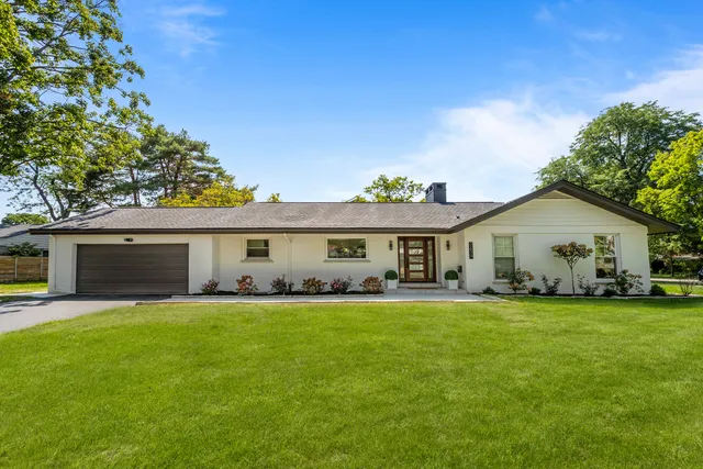 a view of a house with a yard and a large tree