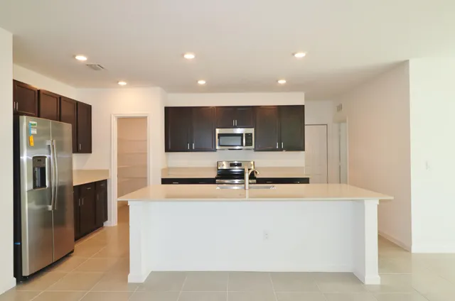 a large kitchen with stainless steel appliances a large counter top a stove and a sink