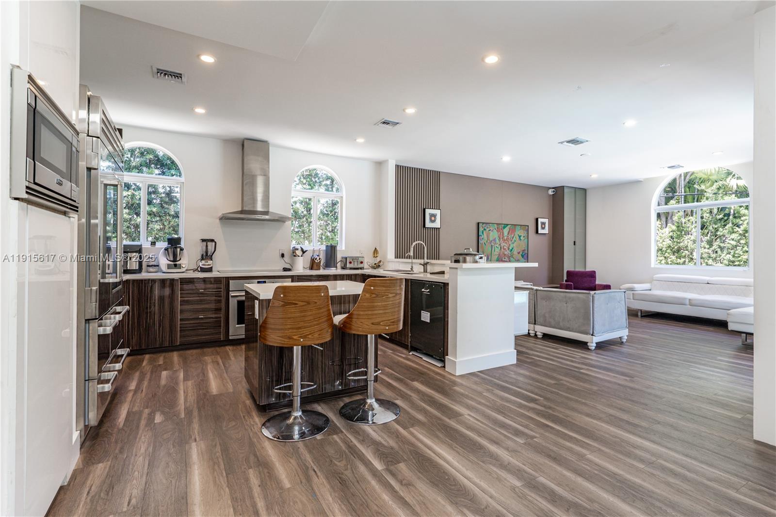 5978 Alton Road Miami Beach, FL 33140 - Photo 13 of 40 a kitchen with stainless steel appliances kitchen island granite countertop a refrigerator a sink dishwasher a dining table and chairs with wooden floor