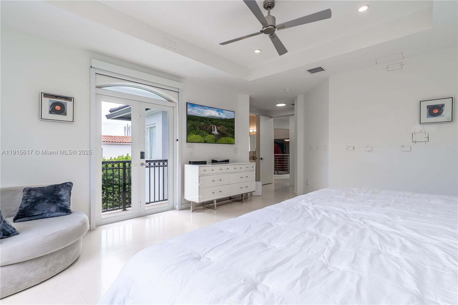 5978 Alton Road Miami Beach, FL 33140 - Photo 27 of 40 a spacious bedroom with a large bed a ceiling fan and a rug