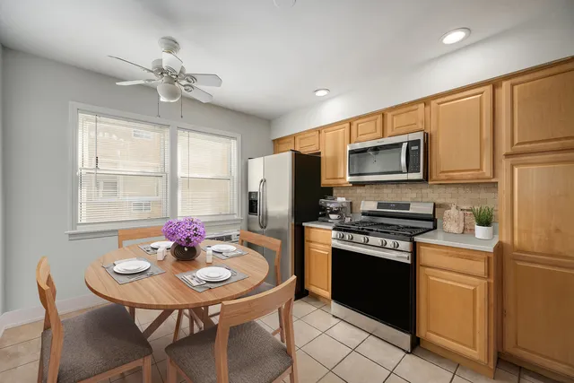 a kitchen with stainless steel appliances a sink a stove a refrigerator dining table and chairs