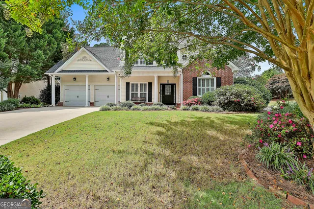 a front view of a house with a yard and trees