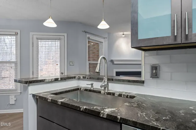 a kitchen with granite countertop a refrigerator a sink and dishwasher