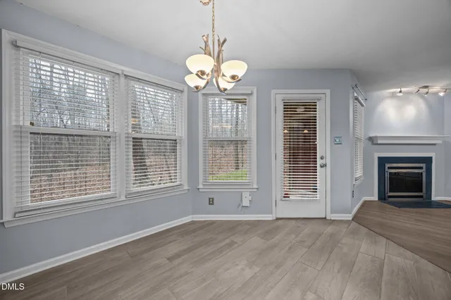 a view of an empty room with wooden floor fireplace and a window