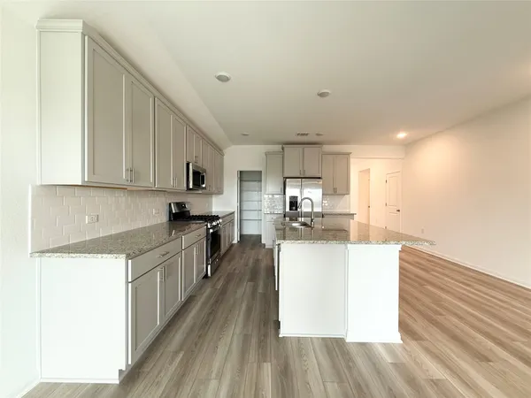 a kitchen with stainless steel appliances granite countertop a sink stove refrigerator and cabinets