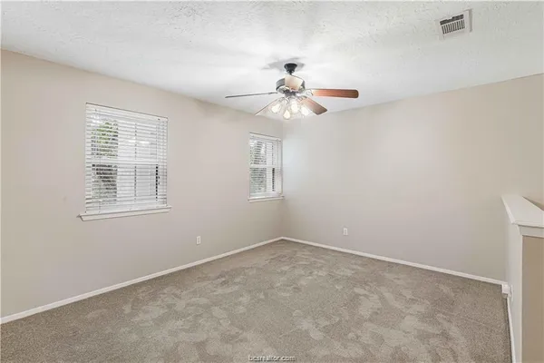 an empty room with windows and fan