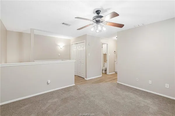 an empty room with closet and a ceiling fan