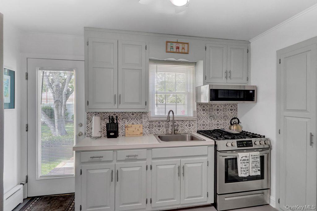 5 Newell Road Merrick, NY 11566 - Photo 7 of 19 a kitchen with white cabinets and a stove